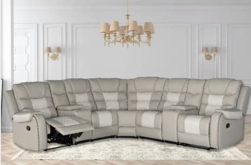 Large gray sectional reclining sofa with white pillows in a modern living room with white walls and gold chandelier
