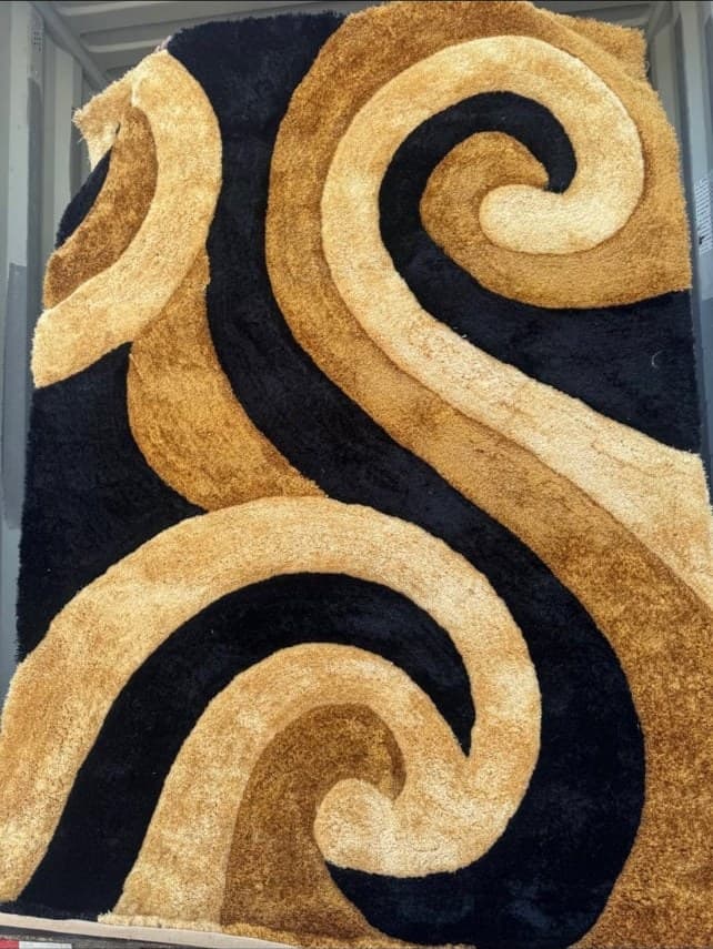 Modern area rug with abstract swirling design in gold, tan, and black colors