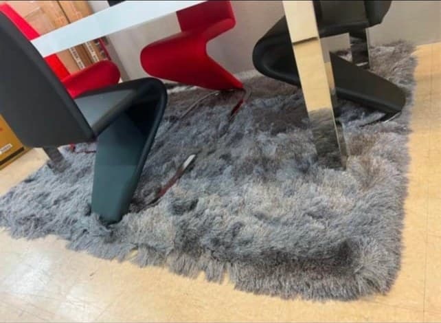 Modern chairs in red, black, and natural tones arranged on a gray shag rug in an interior design showroom