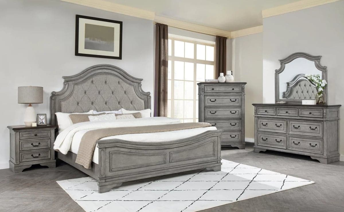 Gray wooden bedroom furniture set including bed, dresser, nightstands, and mirror in a bright bedroom with white walls.