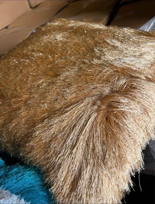 Close-up of a brown and tan furred animal resting on a blue and white fabric surface, showing detailed texture of its coat.