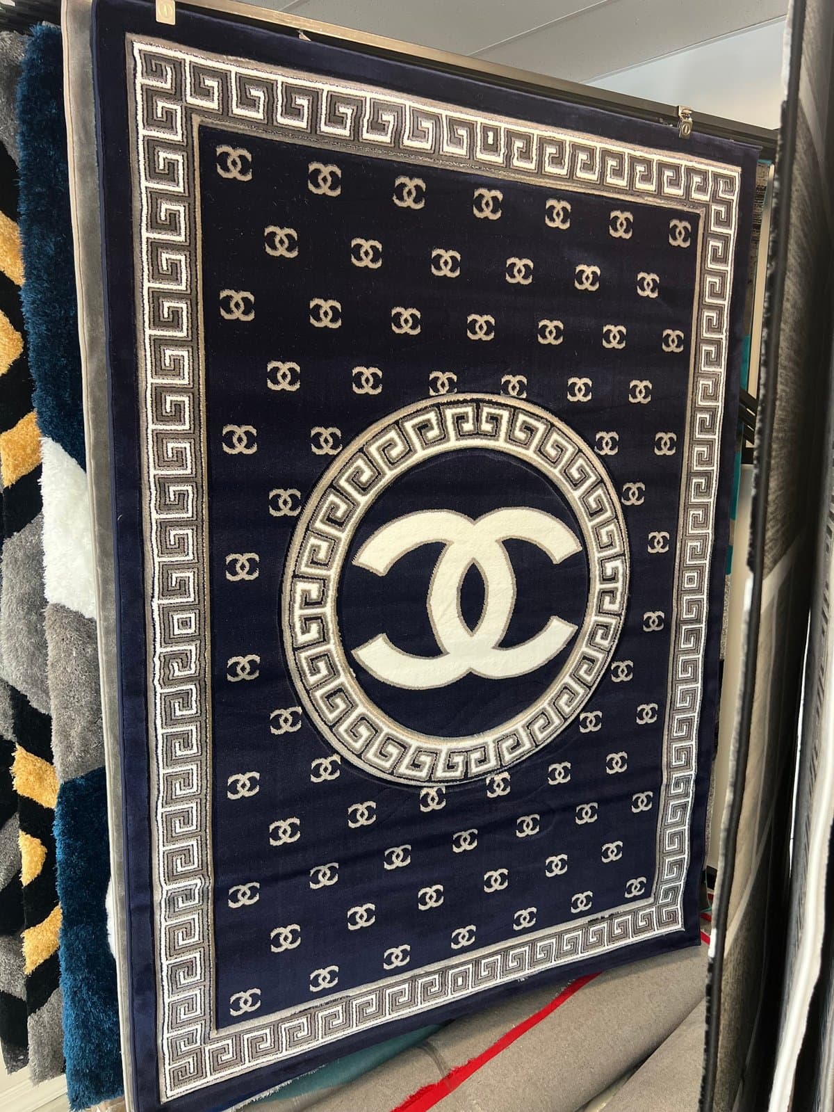 Black and white fabric with repeating CC logos and a large interlocking CC symbol in the center surrounded by a Greek key border pattern